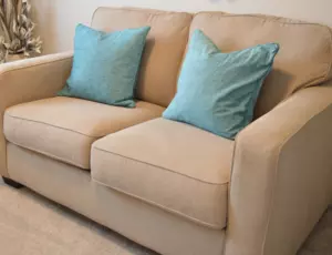 beige sofa in a living room with cushions on