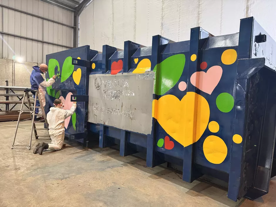 Staff members working on painting a brightly coloured container