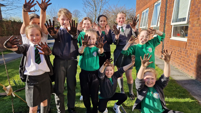 Children waving hands with Veolia staff at a orchard planting session