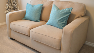 beige sofa in a living room with cushions on