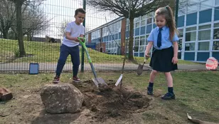 Chidren taking part in Veolia Orchards planting event with a spade and an apple tree