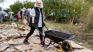 Person walking across a cardboard floor at a No Dig Meadow event with a wheelbarrow in a natural setting
